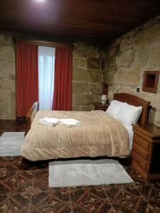 a bedroom with a bed and a stone wall at Cobal 's HOUSE in Viseu