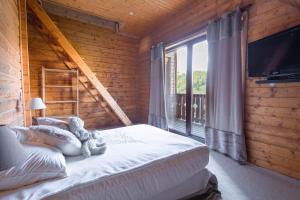 ein Schlafzimmer mit einem Bett und einem großen Fenster in der Unterkunft Chalet Massada vue sur les pistes au coeur de Vallberg - Piscine - Chalet Standing - Jacuzzi - Wifi in Péone