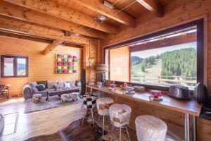 Cabaña de madera con sala de estar con ventana grande en Chalet Massada vue sur les pistes au coeur de Vallberg - Piscine - Chalet Standing - Jacuzzi - Wifi, en Péone