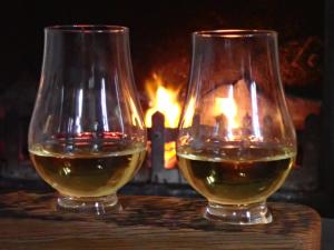 two glasses of wine sitting on a table in front of a fireplace at Linnhe Apartment, Kinlochlaich House in Appin