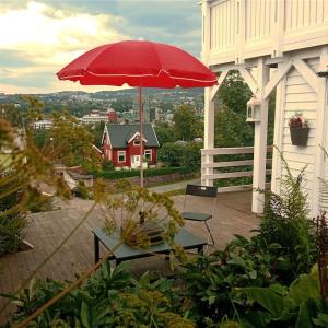 una sombrilla roja en un patio con mesa y sillas en Adorable 1-bedroom apartment with a fantastic view - Free Parking, en Trondheim