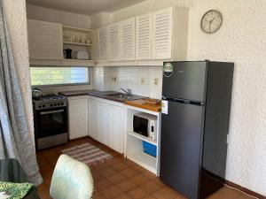 La cuisine est équipée de placards blancs et d'un réfrigérateur noir. dans l'établissement Excelente y práctico, à Punta del Este