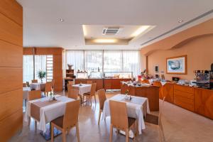 a restaurant with tables and chairs and a kitchen at Athineon Hotel in Rhodes Town