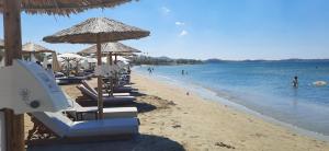 a beach with lounge chairs and umbrellas and the ocean at Parthenis Riviera Hotel in Athens