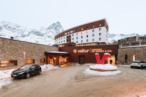 um hotel com um carro estacionado num parque de estacionamento coberto de neve em Valtur Cervinia Cristallo Ski Resort em Breuil-Cervinia