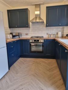 a kitchen with blue cabinets and a stove top oven at Nelson Heights - Perfect seaside retreat, Cromer in Cromer