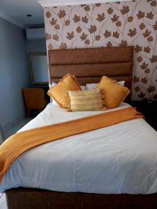 una camera da letto con un grande letto con cuscini gialli di R&R GUEST HOUSE a Lenyenye