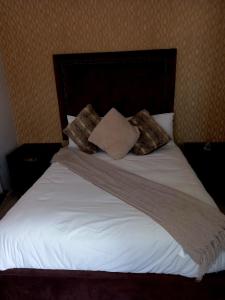 un letto con lenzuola e cuscini bianchi di R&R GUEST HOUSE a Lenyenye