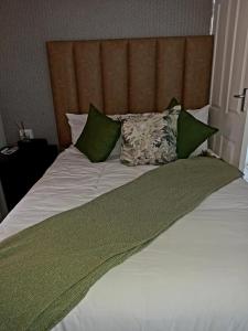a large bed with green and white sheets and pillows at R&R GUEST HOUSE in Lenyenye