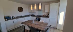 a kitchen with a wooden table and white cabinets at Parkside, Perranporth in Perranporth