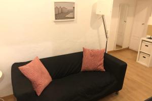 a black couch with two pillows in a living room at NEW! Apartment in Sarria near Metro in Barcelona