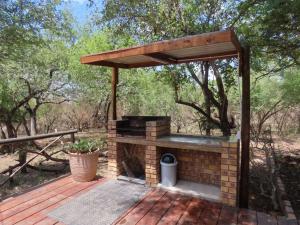 a brick fireplace with a wooden roof on a deck at Bush and Gables House in Marloth Park