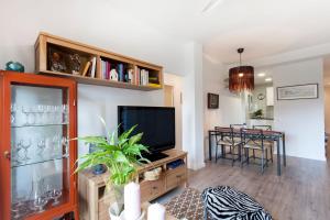 a living room with a television and a dining room at Cozy Apartment near Fira Gran Via with AC in Hospitalet de Llobregat