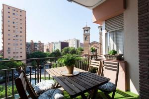 a wooden table on a balcony with a view of a city at Cozy Apartment near Fira Gran Via with AC in Hospitalet de Llobregat