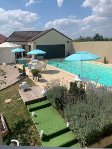 una piscina con sillas y sombrillas y una piscina en LA DOLCE VITA en Bretenière