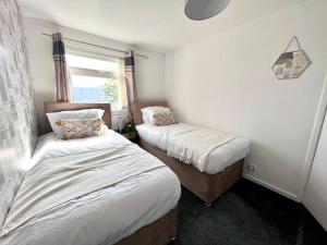 two beds in a small room with a window at Three bedroom house, close to airport, A1, NCL in Kenton