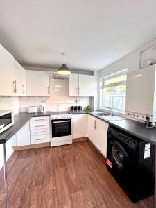 cocina con armarios blancos y lavavajillas negro en Three bedroom house, close to airport, A1, NCL en Kenton