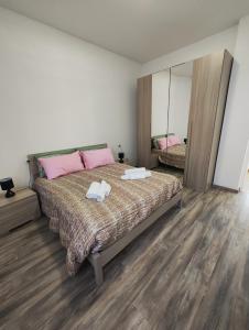 ノヴァーラにあるAppartamento c&y Torelli 1のベッドルーム1室(ピンクの枕と鏡付きのベッド1台付)