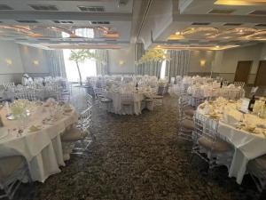 un salón de banquetes con mesas y sillas blancas en Riverside Lodge Hotel, en Irvine