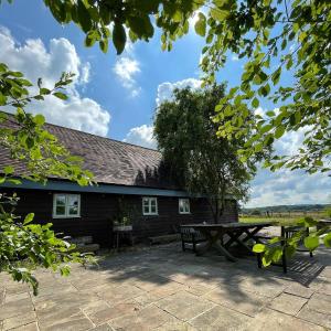 a picnic table and bench in front of a building at House on the Brooks Self catering Holiday let South Downs West Sussex Sleeps 14 in Pulborough