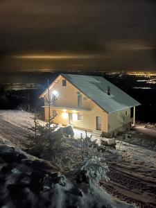 a house in the snow at night at Pensiunea Sarah-Muntele Mic in Muntele Mic