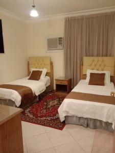 a hotel room with two beds and a television at Dar Al Riyadh Apartments in Riyadh