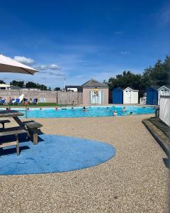 a swimming pool with a picnic table and an umbrella at Berwick Holiday Park Haven in Berwick-Upon-Tweed