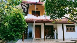 a small white house with a porch and trees at Dini's home stay in Matara
