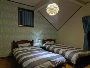 a bedroom with two beds and a chandelier at HARUNA SKY Panoramic view of Nasu,private space surrounded by fir trees,relaxing stone bath,watching movies on a 120inch big screen in Nasu