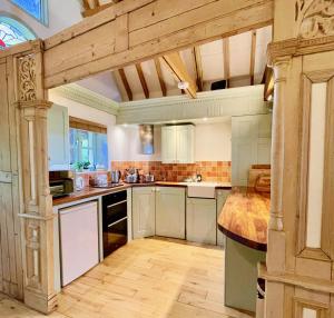 a large kitchen with white cabinets and a wooden floor at House on the Brooks Self catering Holiday let South Downs West Sussex Sleeps 14 in Pulborough +21 photos