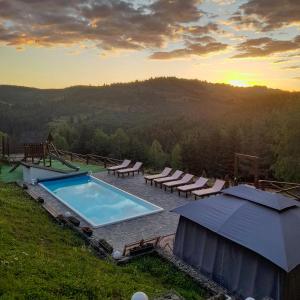 uma piscina numa colina com cadeiras e um pôr-do-sol em Villa Debryanets em Rozhanka Nizhnyaya