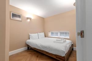 a bedroom with a bed with white sheets and a window at GuestReady - Beige barley near museum in London