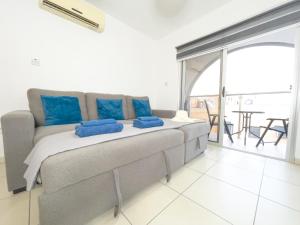 un salon avec un canapé avec des coussins bleus dessus dans l'établissement Pandora Holiday Apartment Ayia Napa, à Ayia Napa