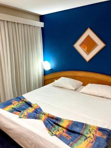 a bedroom with two beds and a blue wall at Hotel Flat Classic in Fortaleza