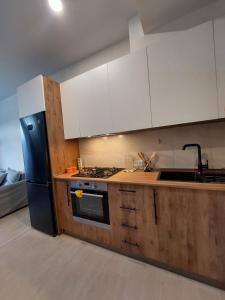 a kitchen with white cabinets and a black refrigerator at Bakuriani Ski Apartment-Didveli Tulip A34 in Bakuriani