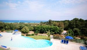 a large swimming pool with chairs and umbrellas at Le Cocon Bord de mer in Belgodère