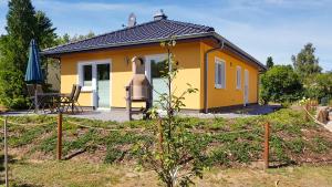 een klein geel huis met een grill in een tuin bij Ferienhaus Zur Mühle in Freest