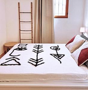 a bed with a white blanket with drawings on it at Le Cocon Bord de mer in Belgodère