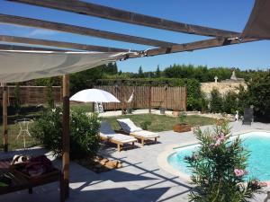 un patio con piscina, sombrilla y mesa en L'EN HAUT, en Aramon