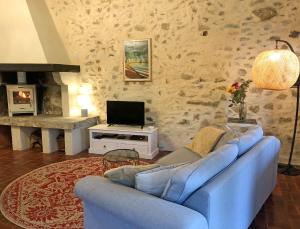 a living room with a blue couch and a tv at Gîtes de Montcabirol - Malepère in La Bastide-de-Bousignac