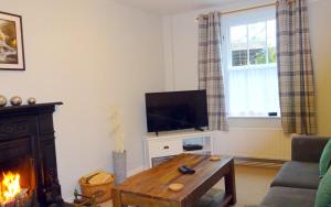 a living room with a fireplace and a television at Cherry Cottage, Youlgrave Nr Bakewell in Youlgreave
