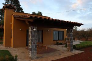 een klein geel huis met een dak bij Casa Aralias in Zacatlán