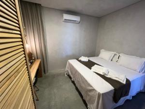 um pequeno quarto com uma cama com lençóis brancos em Uhane Luxury Villas em São Miguel do Gostoso