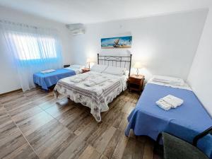 two beds in a room with blue sheets at Nuevo Hotel Parador in Roldán