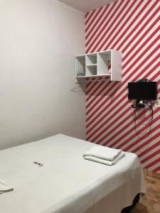 Zimmer mit einem weißen Bett und einer rot-weißen gestreiften Wand in der Unterkunft Novo Hotel in Carolina