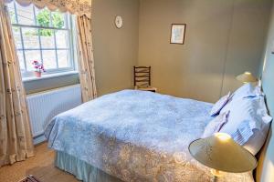 Un dormitorio con una cama azul y una ventana en Bragborough Hall Coach House en Braunston