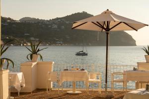 a table with an umbrella and a boat in the water at Miramare Sea Resort & Spa in Ischia