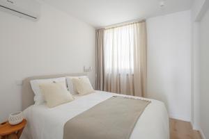a white bedroom with a white bed and a window at Lapa 84 - seafront house in Póvoa de Varzim