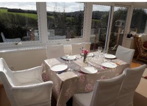 a table with white chairs and a table with plates and glasses at Curlews Cottage - House with 3 bedrooms and garden - walking distance to the beach in Perranporth