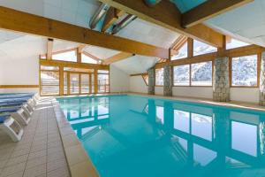 a swimming pool with blue water in a building with windows at Chalet JL et DS , Pied des pistes, Valmeinier 1800, 10 pers. in Valmeinier